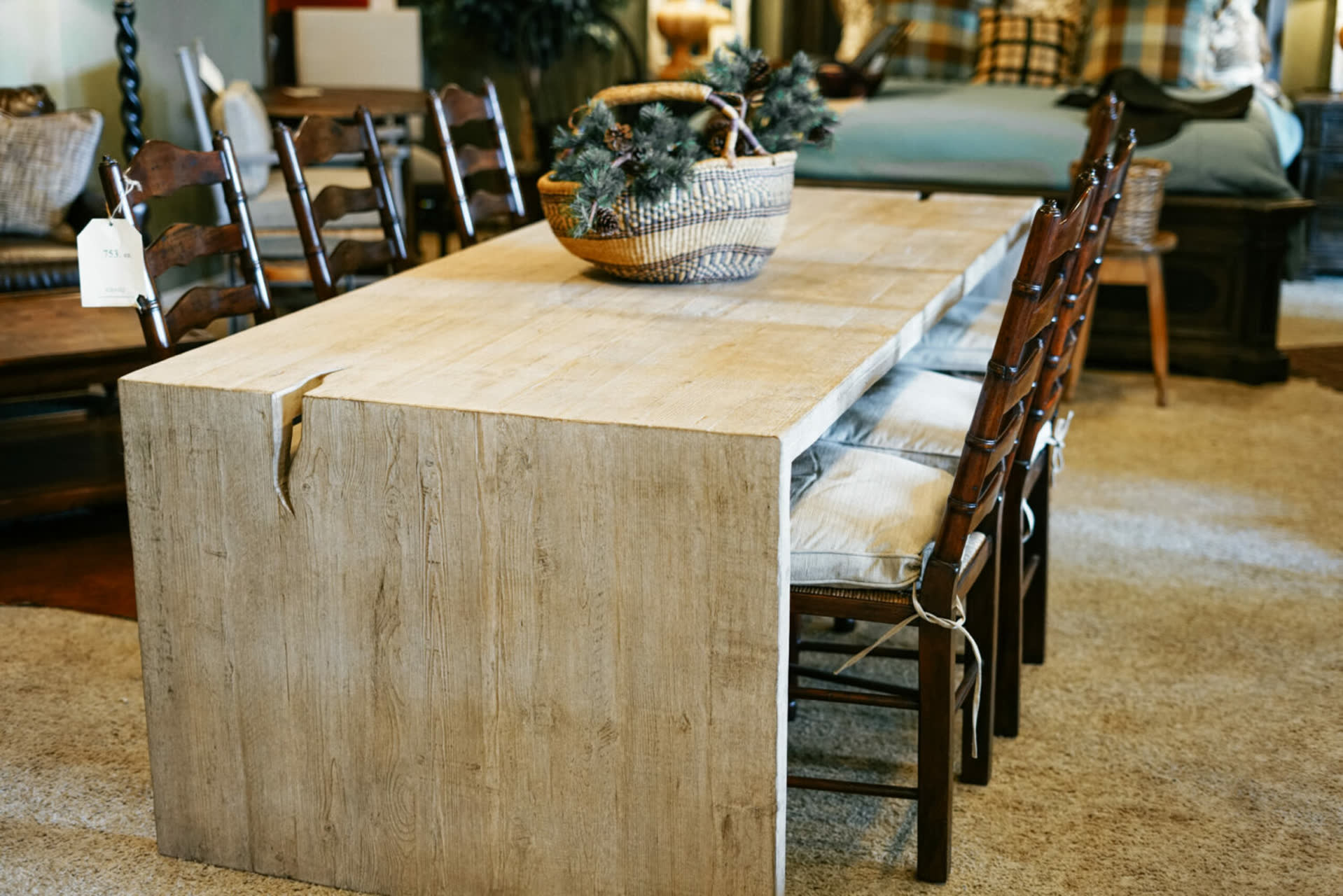 Bleached oak plank dining table with ladder-back chairs and a woven basket centerpiece in the Koontz showroom